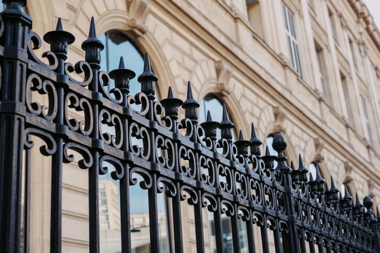 Ornate iron fence in front of historic building with arched windows.